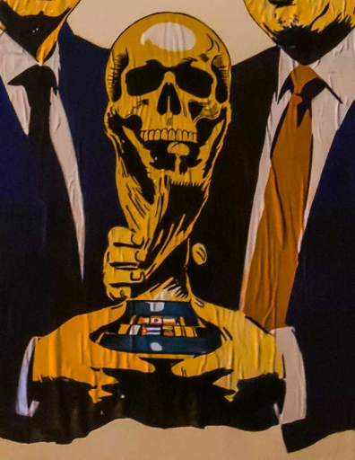 Il presidente degli Stati Uniti Donald Trump e il presidente della Fifa Gianni Infantino stringono, sorridenti, la ‘Death Cup’, “la coppa della morte”, ossia la coppa dei mondiali di calcio che la posto del pallone presenta un teschio: è l’ultima denuncia della street artist Laika1954, tra le più impegnate in materia di diritti umani e denunce sociali.