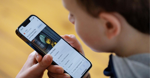 un minore guarda la schermata di uno smartphone